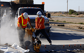 Two people working on a road.